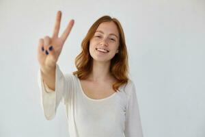 young positive female shows v sign into camera photo