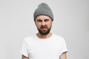 A disgruntled male model of a wrinkled face, makes a grimace of disgust, purses face, twists his mouth, expresses discontent, irritation. People and negative facial expressions photo