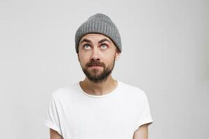 Curious blue-eyed man in a gray hat glances with interest up, saw something unusual flying plane or a new signboard, a large store, large building. Thinking about something photo