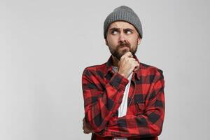 Thoughtful young man holding hand on chin and looking away standing isolated over white background. Copy space for advertisement.Ponders the idea, doubts, weighs possible options photo