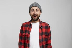 Studio shoot of shocked young male, expresses great surprised. Mouth and eyes are widely opened, isolated over white background. Positive successful young man has overjoyed expression photo