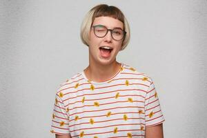 Closeup of happy playful beautiful young woman wears striped t shirt and spectacles flirting and winking isolated over white background photo