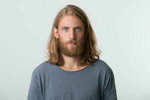 Closeup of serious attractive young man with beard and blonde long hair wears gray t shirt looks pensive and thoughtful isolated over white background photo