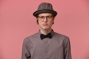 Closeup portrait skeptical young man looking disrespectful, dissatisfied, pessimistic, full of distrust, isolated pink background. Negative human emotion facial expression, feeling attitude photo