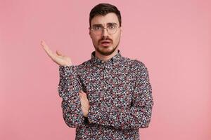 Clueless confused male unshaved dressed in colorful shirt reaised palm in uncertainty, talks indignantly about something, argues. Hesitant man doesnt know how change future life photo