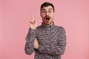 Excited man came up with something incredible, unique, brilliant,found a non-standard solution,overflowed positive emotions from the thought in his head,finger raised up, mouth opened, pink background photo