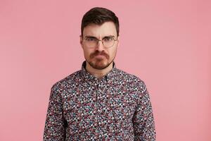 Young handsome bearded man with an angry, aggressive and facial expression, ready for the fight, showing furiousite and belligerent. photo