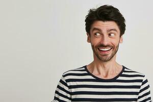 Portrait of cheerful handsome bearded young man wears striped t shirt smiling and looks to the side isolated over white background photo