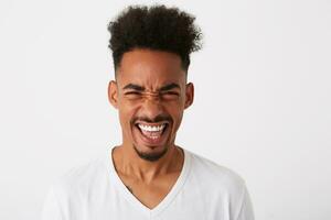 retrato de alegre emocionado africano americano joven hombre con Rizado pelo usa t camisa siente emocionado y riendo aislado terminado blanco antecedentes foto