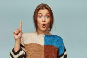 Young girl in checkered sweater and a bright make-up came up with a great idea Model woman inspired excited isolated on bright blue background photo