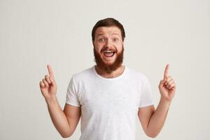 Portrait of cheerful excited young man with beard wears t shirt feels happy photo