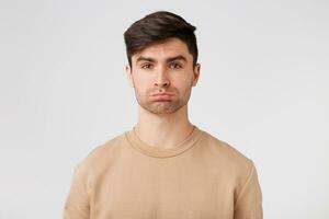 Cute attractive brunet with light stubble looks sad offended upset displeased. On the street bad weather and a date with his girlfriend canceled photo