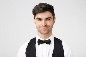Confident flirting handsome smartly dressed dark-haired guy with black bow tie,looks charming inviting, all girls want to dance with him, isolated over white background photo