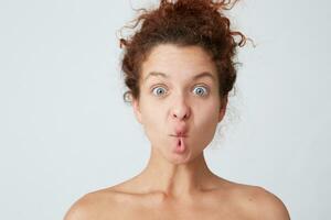 Cropped shot of funny cute young woman with curly hair and healthy skin making fish face with lips and having fun isolated over white wall Comical expression photo