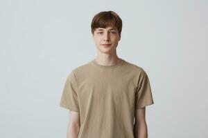 Portrait of handsome attractive young man with short haircut and blue eyes wears beige t shirt standing and smiling isolated over white background Looks directly in camera photo