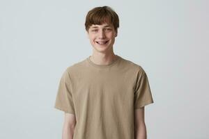 smiling handsome young man with healthy teeth and metal braces wears beige t shirt and looks directly in camera isolated over white background Feels happy and thinks about girlfriend photo