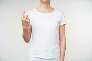 Indoor photo of young lady showing index finger while meaning word whence on sign language, isolated over white background. Hand gestures of people with hearing impairment