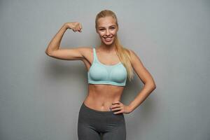 Portrait of positive sporty long haired blonde female looking happily to camera photo