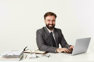 Portrait of a young successful businessman working at his laptop and smiling at the camera. photo