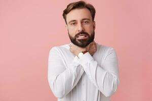 Young bearded man try kill himself, strangling himself with both hands and choking isolated over pink background. photo