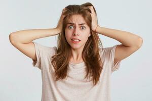 retrato de loco irritado joven mujer con manos en cabeza usa t camisa siente enojado y enojado aislado terminado blanco antecedentes foto