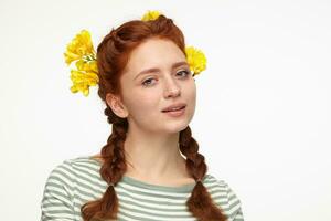 Indoor portrait of young ginger female posing over white background looking into camera with calm facial expression photo