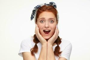 close up of ginger young female looking into camera with shocked facial expression photo