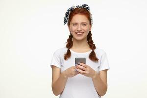 smiling ginger young female holding phone photo