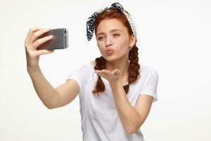 ginger young female making selfie and send air kiss photo