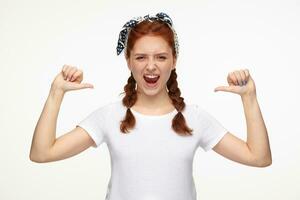 ginger young female points with thumbs at herself photo