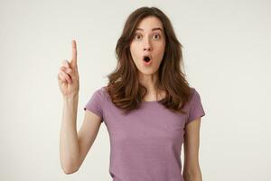 Young happy woman with beautiful hair over isolated background pointing finger up with successful idea. Number one.Girl expressing surprise while gasping and glancing with dropped jaw at camera photo