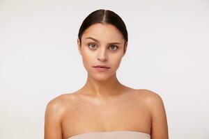 Puzzled young pretty brunette green-eyed woman wearing casual hairstyle while posing over white background, raising confusedly eyebrow while looking to camera photo