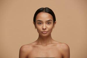 Beautiful caucasian girl, looking camera like in the mirror, after a skincare and spa, with healthy clean fresh skin after the procedure. Attractive fashion model over beige background photo