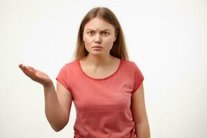 Indoor photo of severe young blonde lady with casual hairstyle frowning eyebrows while looking seriously at camera and keeping palm raised, isolated over white background