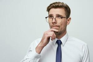 Young businessman with serious face expression thinking about question, concentrated on some idea,thoughtfully touching his chin and looking into the distance, dressed in white shirt,white background photo