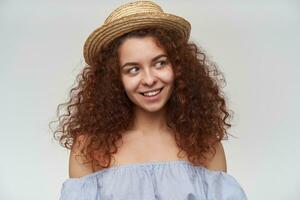 Portrait of attractive, adult redhead girl with curly hair. Wearing striped off-shoulders blouse and hat. Watching to the right at copy space, closeup, isolated over white background photo