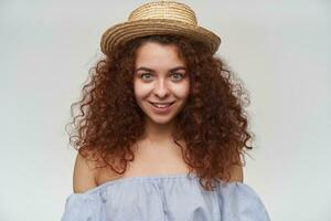 Teenage girl, happy looking woman with curly ginger hair. Wearing striped off-shoulders blouse and hat. Watching at the camera and smiling, closeup, isolated over white background photo