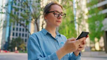 Caucasian woman in glasses walking around the city and using smartphone video