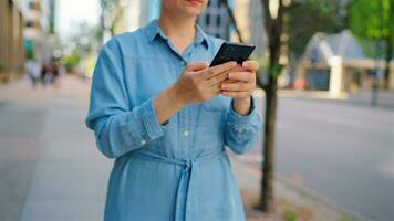 caucásico mujer en lentes caminando alrededor el ciudad y utilizando teléfono inteligente video