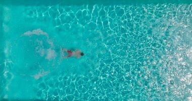 Antenne Aussicht wie ein Mann Tauchgänge in das Schwimmbad und schwimmt. schleppend Bewegung video