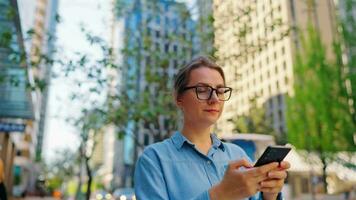 Caucasian woman in glasses walking around the city and using smartphone video