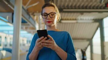 femme des stands à une transport Arrêtez et en utilisant téléphone intelligent. lent mouvement video