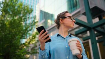 Caucasian woman in glasses stands on the street and using smartphone video