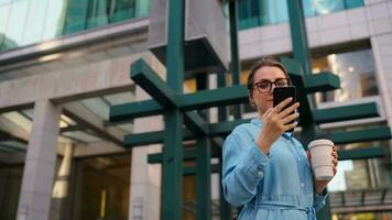 Caucasian woman in glasses stands on the street and using smartphone video