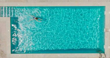 aereo Visualizza di un' donna nel blu costume da bagno nuoto nel il piscina. estate stile di vita video