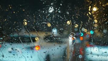 luces de el noche ciudad y paso carros mediante un mojado lluvioso ventana. video