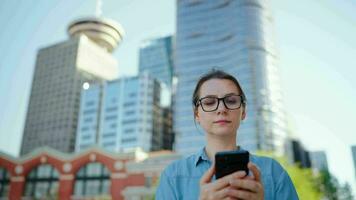 Caucasian woman in glasses walking around the city and using smartphone video