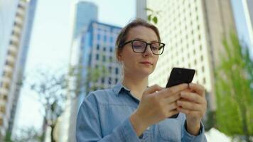 Caucasian woman in glasses walking around the city and using smartphone video