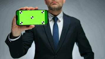 Man shows smartphone with green screen chroma key smartphone on camera. video