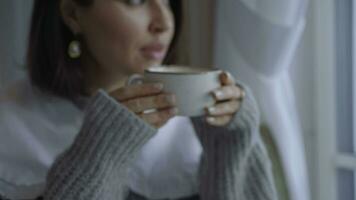 uma menina goza uma café em uma inverno manhã. uma menina dentro uma suéter tem café da manhã video